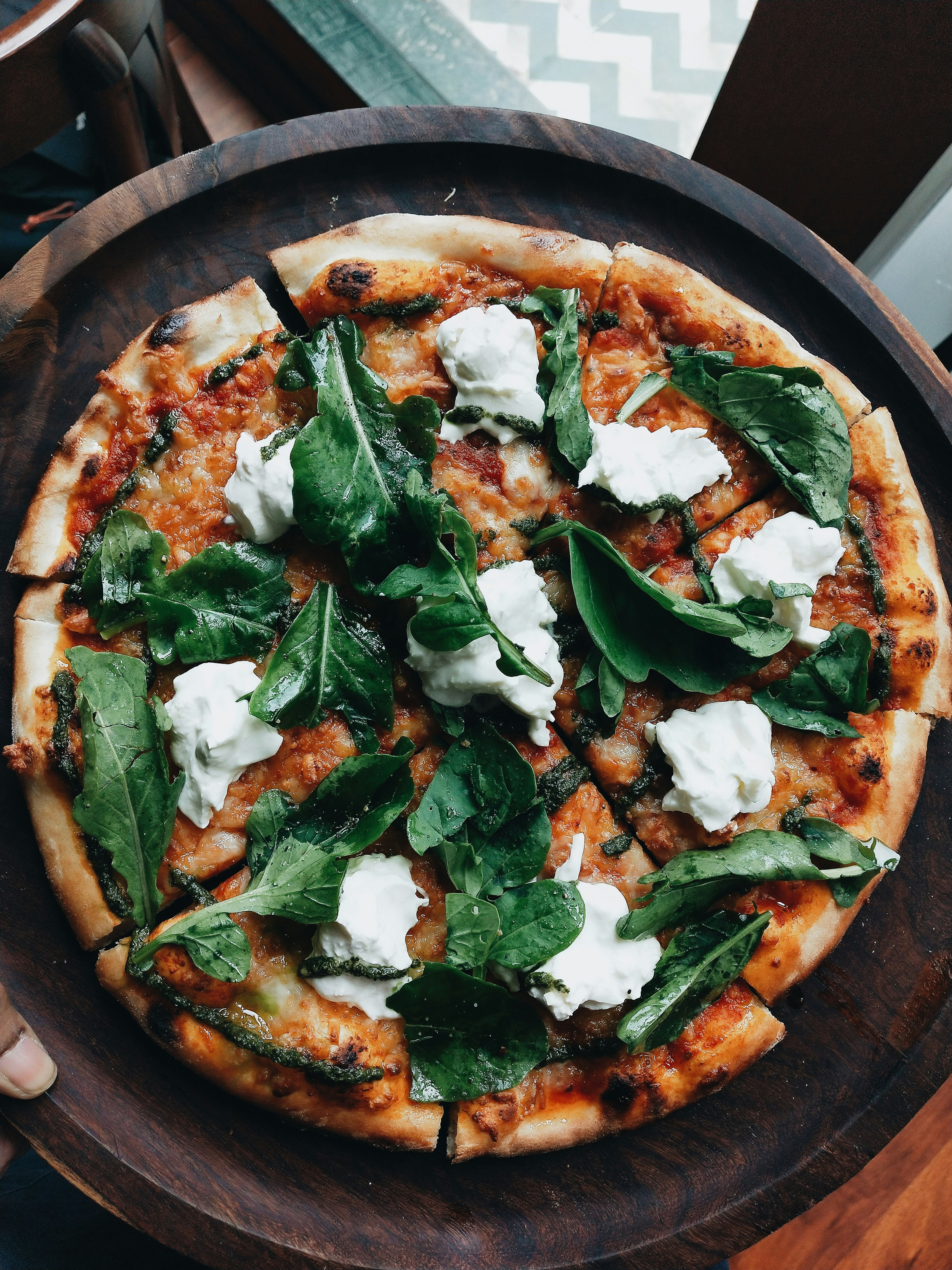 Hand som toppar pizzan med färska råvaror